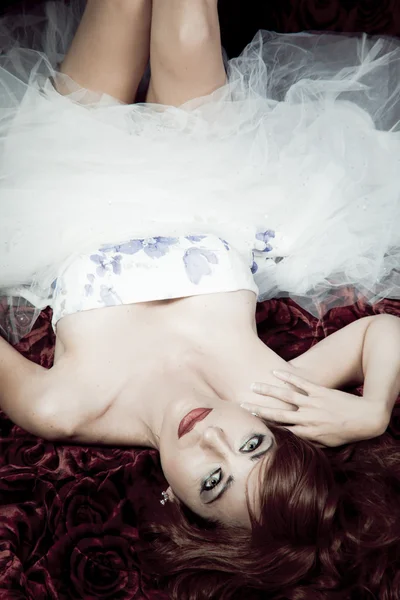 红发美女躺在床上的玫瑰 — 图库照片