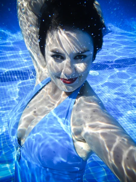 Vintage girl simning och leende under vattnet i en pool — Stockfoto