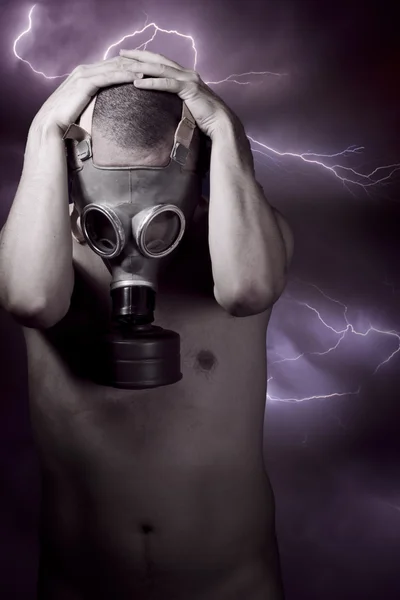 Man in een gas masker kijken vloer, storm op achtergrond — Stockfoto