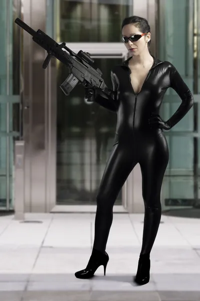 Sexy kobieta trzyma pistolet na sobie sukienkę czarną skórą — Zdjęcie stockowe