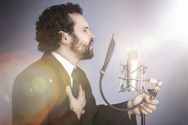 Uomo che canta con abito nero e microfono — Foto Stock