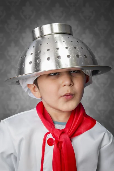 Een grappige kleine jongen kook in uniform op vintage achtergrond — Stockfoto