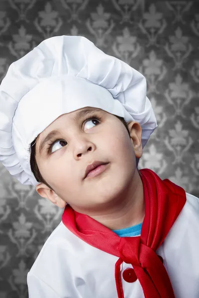 Gelukkige jongen cook in uniform over vintage achtergrond grappig kijken — Stockfoto