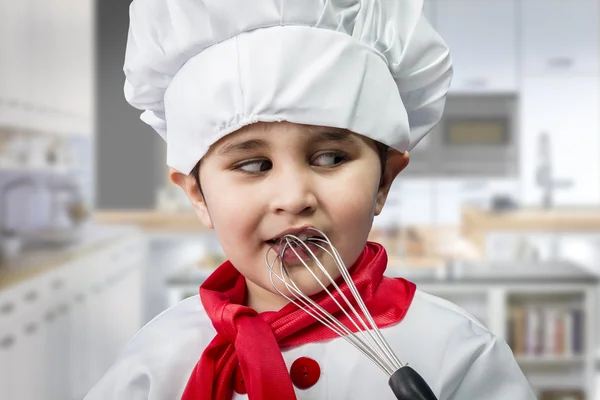 Chico divertido vestido de chef, cocinando en una cocina — Foto de Stock