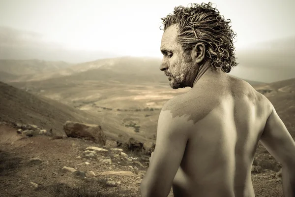 Warrior man covered in mud on desert background — Stock Photo, Image