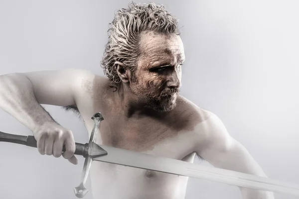 Warrior man covered in mud with sword — Stock Photo, Image