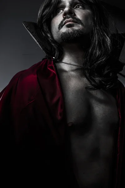 Sensuale giovane vampiro con cappotto nero e capelli lunghi, nudo — Foto Stock