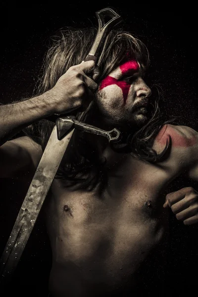 Naked warrior carrying huge steel sword, painted face — Stock Photo, Image