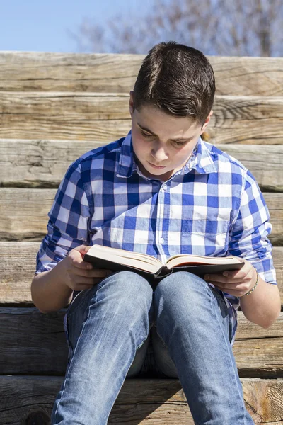 Jongen leest een boek in het park — Stockfoto