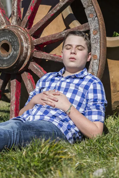 Niño acostado al lado de una rueda de carro — Foto de Stock