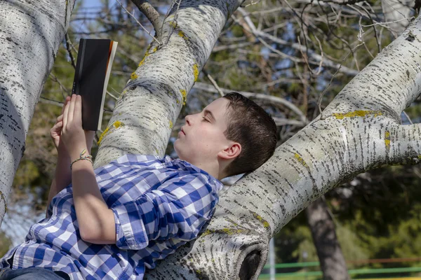 Junge liest draußen ein Buch — Stockfoto