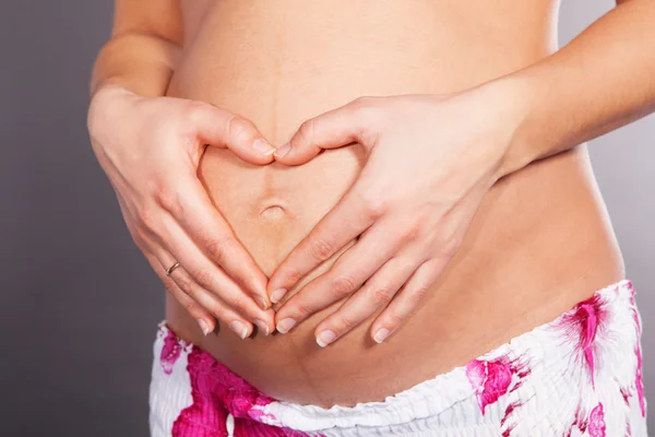 Dettaglio della donna incinta che forma forma forma di cuore con le mani — Foto Stock