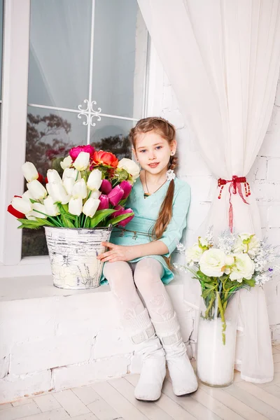 Schattig klein kind meisje met Lentebloemen, gelukkig babymeisje met mand van bloemen. — Stockfoto