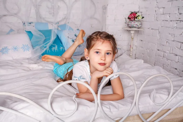 Schönes kleines Mädchen sitzt auf weißer Decke in ihrem Schlafzimmer — Stockfoto
