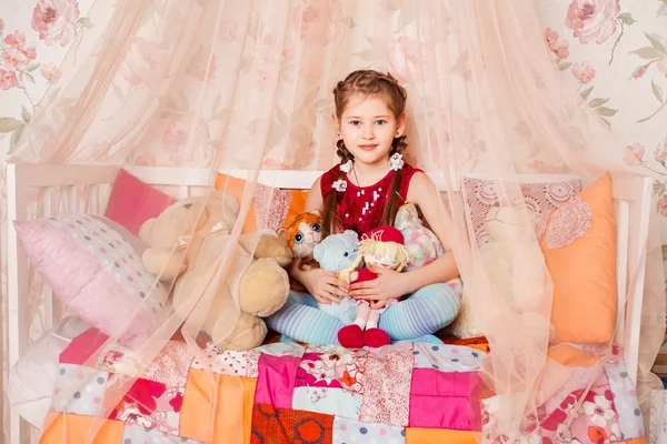 Schönes kleines Mädchen sitzt auf weißer Decke in ihrem Schlafzimmer — Stockfoto