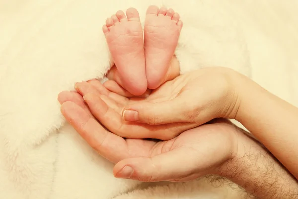 Bebé recién nacido pies en manos femeninas — Foto de Stock