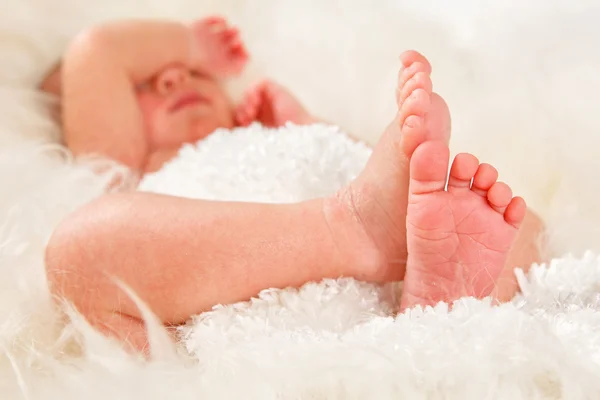 Newborn 12 day old baby boy lying on his back relaxing under a wrap cloth. Portrait old newborn baby boy wearing a gold crown. — Stock Photo, Image