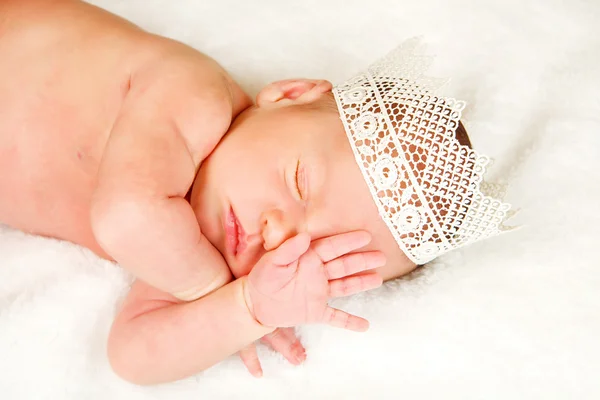 Newborn 12 day old baby boy lying on his back relaxing under a wrap cloth. Portrait old newborn baby boy wearing a gold crown. — Stock Photo, Image