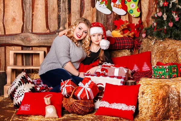 Jonge moeder en haar dochter bij een open haard op Kerstmis — Stockfoto
