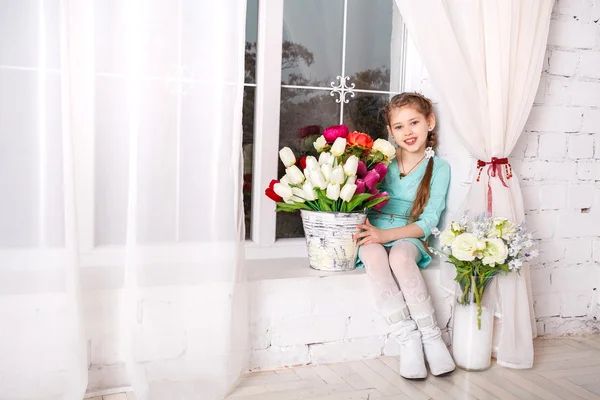 Petite fille mignonne avec des fleurs de printemps, heureuse petite fille avec panier de fleurs . — Photo