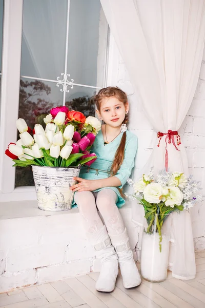 Petite fille mignonne avec des fleurs de printemps, heureuse petite fille avec panier de fleurs . — Photo