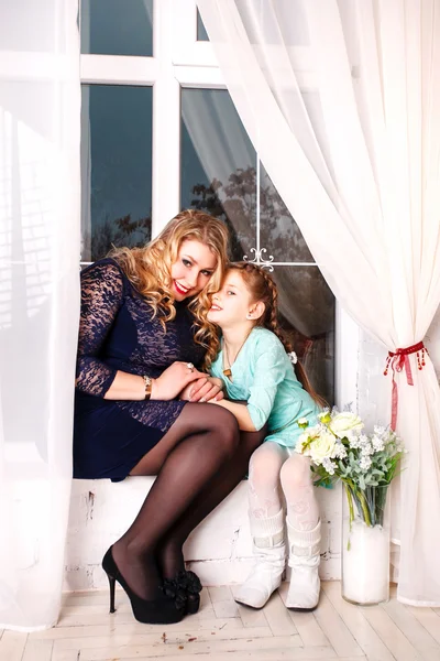 Madre e hija pequeña con flores. Primer plano de afectuosa madre e hija en casa — Foto de Stock