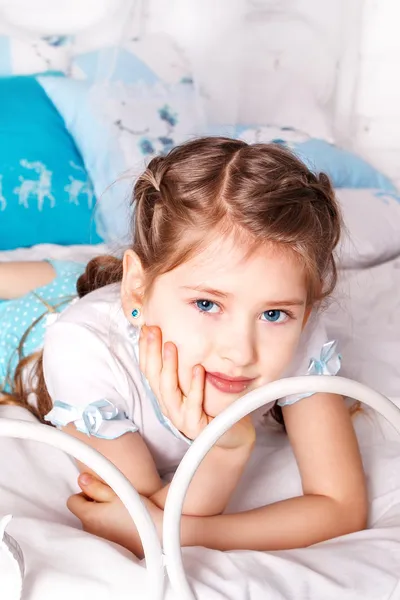 Schönes kleines Mädchen sitzt auf weißer Decke in ihrem Schlafzimmer — Stockfoto