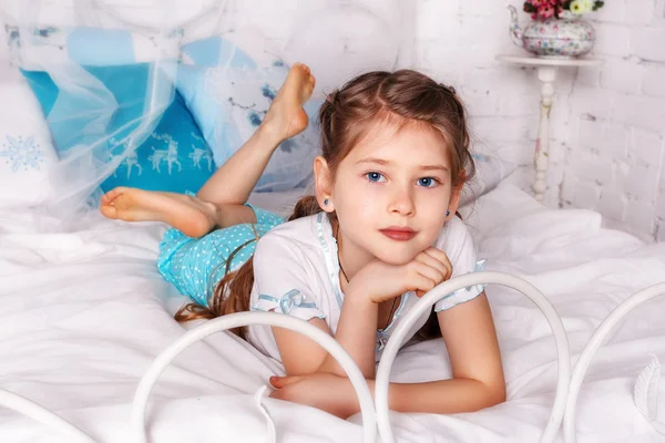 Schönes kleines Mädchen sitzt auf weißer Decke in ihrem Schlafzimmer — Stockfoto