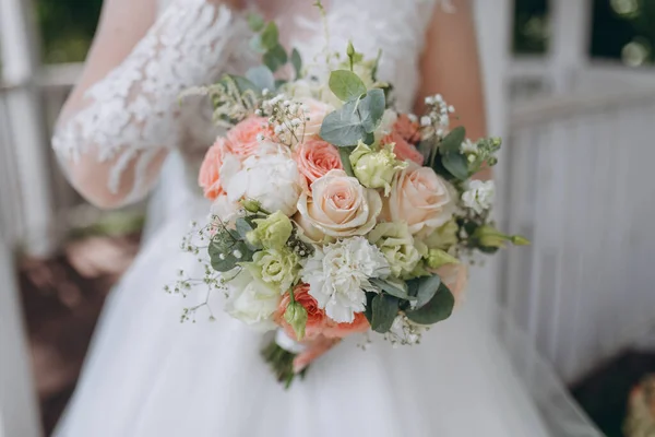 Estilo, arranjo floral, conceito de casamento. jovem mulher vestida com vestido branco nevado extremamente bonito com saia inchada está segurando grande monte de flores diferentes esticadas com fitas amarelas . — Fotografia de Stock