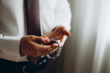 İş adamı kol saatini kontrol ediyor, saati eline alıyor, damat düğün töreninden önce hazırlanıyor..