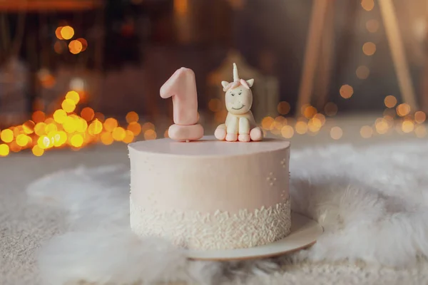 Birthday candle as number one on top of sweet cake and pink unicorn on table, concept image — стоковое фото