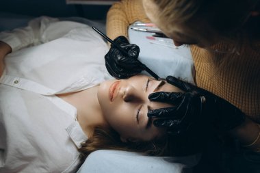 Güzellik salonunda profesyonel kaş düzeltme prosedürü olan genç bir kadın. .