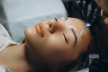 Güzellik salonunda profesyonel kaş düzeltme prosedürü olan genç bir kadın. .
