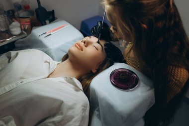 Güzellik salonunda profesyonel kaş düzeltme prosedürü olan genç bir kadın. .