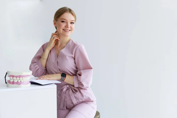 beauty and medicine, professional dental treatment, doctor, dentist, woman sits at the desk and makes an entry in the work schedule. High quality photo