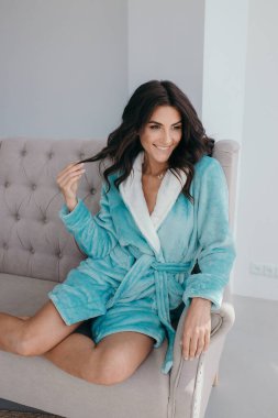 Evde banyo yaptıktan sonra bornoz ve spa havlusuyla rahatlayan sağlıklı, genç bir kadın. Güzellik, dinlenme ve vücut bakımı prosedürleri. Yüksek kalite fotoğraf