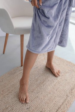 Beyaz bornozlu bir kızın büyük pencereli bir odada küvetin yanında durduğunu hayal et. Yüksek kalite fotoğraf