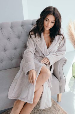 Beyaz bornozlu bir kızın büyük pencereli bir odada küvetin yanında durduğunu hayal et. Yüksek kalite fotoğraf