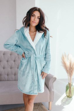 Beyaz bornozlu bir kızın büyük pencereli bir odada küvetin yanında durduğunu hayal et. Yüksek kalite fotoğraf