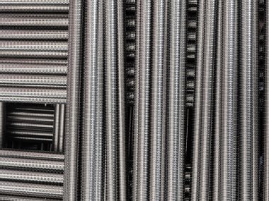 Stainless steel threaded rods stacked on top of each other.