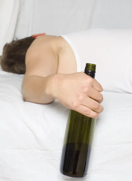 Чоловік у ліжку з пляшкою вина — стокове фото