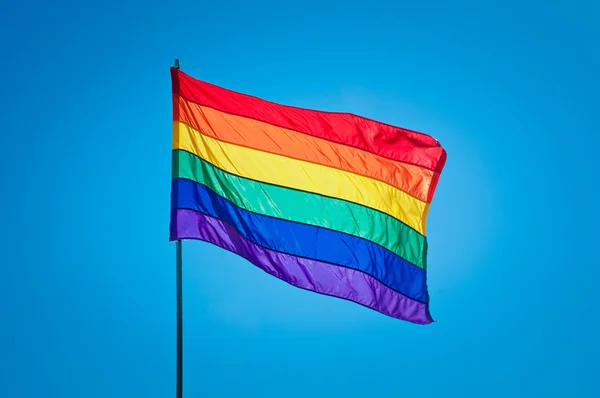 Drapeau de fierté gay arc-en-ciel sur fond bleu ciel Image En Vente