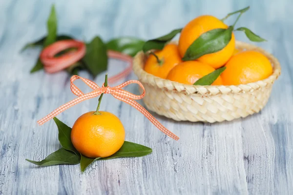 Um mandarim perto do cesto com outras mandarinas. Rolo de fita no fundo — Fotografia de Stock