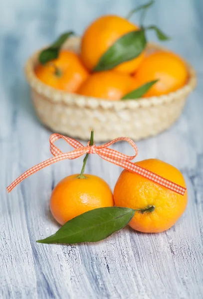 Dvě mandarinky na staré modro bílý stůl u košíku s mandarinek — Stock fotografie
