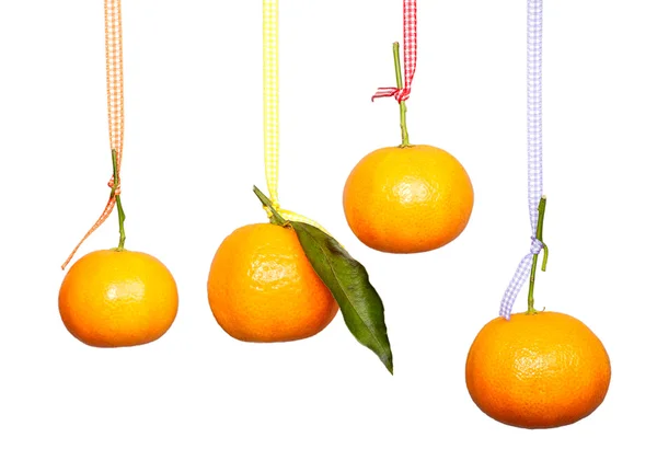 Four mandarins are hanging on the colored tape against the white background. Isolated. Royalty Free Stock Photos