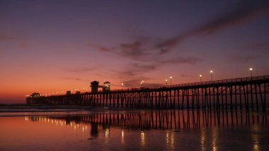 İskele silueti Oceanside California USA. Okyanus gelgiti tropik plaj. Yaz zamanı parlayan atmosfer.