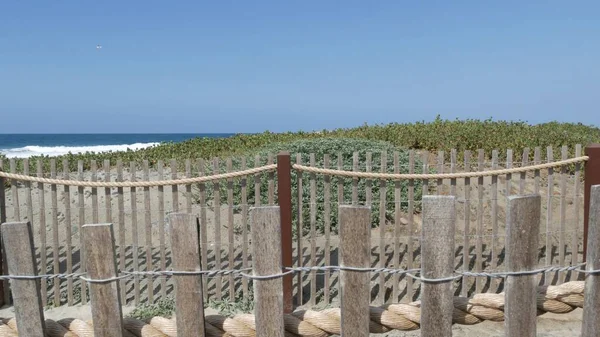 Summer waves on beach, California shoreline USA. Pacific ocean coast, picket fence on sea shore. — Stock Photo, Image