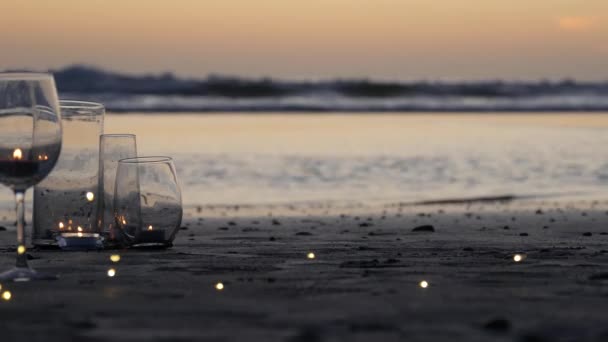 촛불 불빛은 유리에, 로맨틱 한 해변은 바다의 파도에 의해, 여름의 바다에 의해 시작됩니다. 모래 위에 촛불. — 비디오