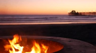 Oceanside Rıhtımı 'ndaki kamp ateşi çukuru, Kaliforniya ABD. Okyanus sahilinde yanan kamp ateşi, BBC için çimentoda yanan şenlik ateşi, deniz suyu dalgaları. Romantik akşam alacakaranlığı, yaz gün batımından sonra alacakaranlık..
