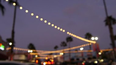 Elektrikli çelenkler, Kaliforniya 'da palmiye ağaçları. Sahil gün batımı, sahil alacakaranlığı gökyüzü. Los Angeles ışıkları.